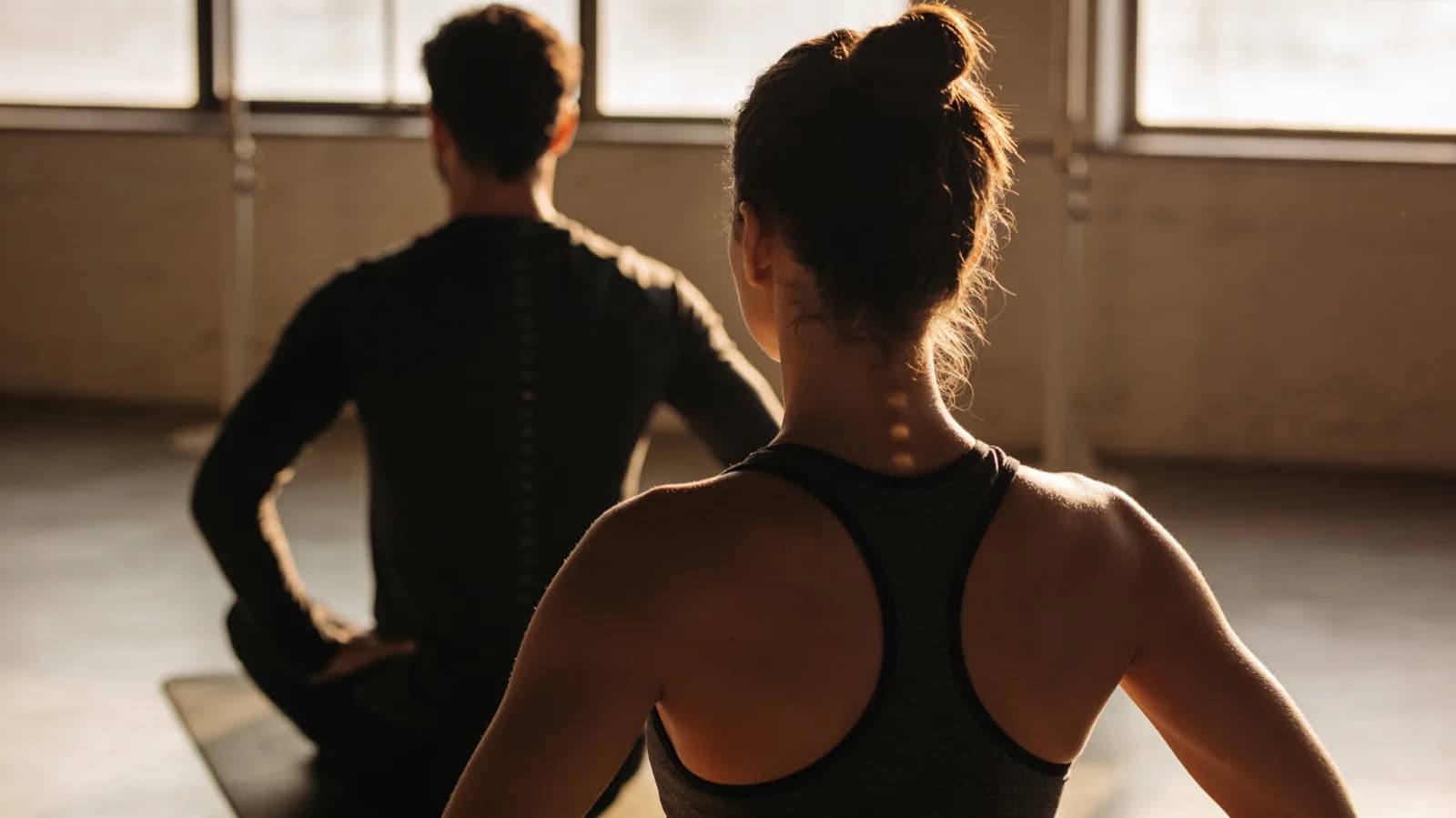 Two people holding a plank, seen from behind against the light